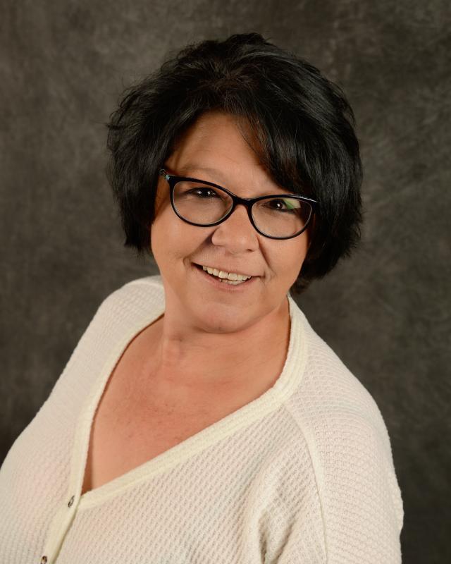 Smiling woman with glasses and dark hair.