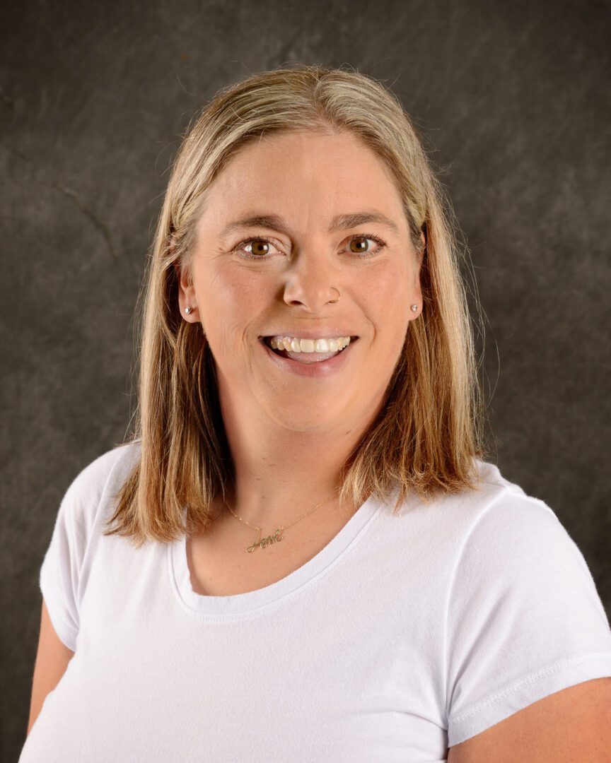 Smiling woman with blonde hair wearing a white top.