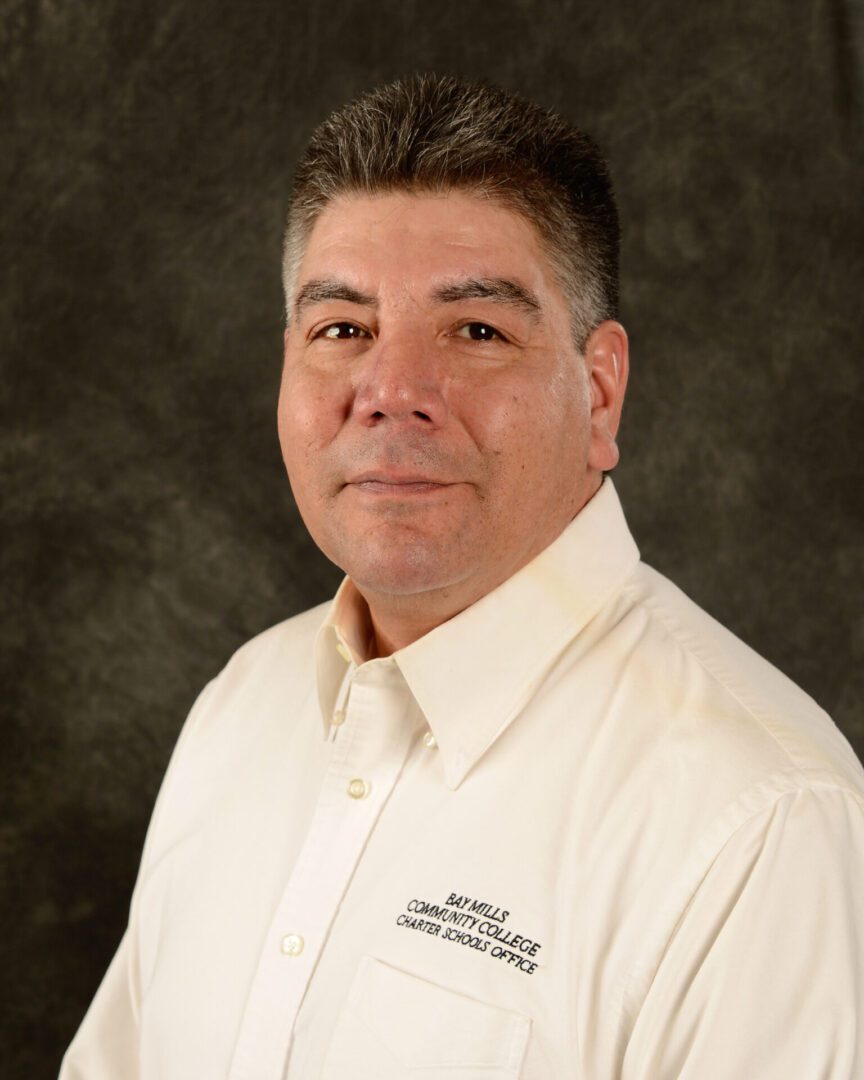 Portrait of a man in a white collared shirt against a dark background.
