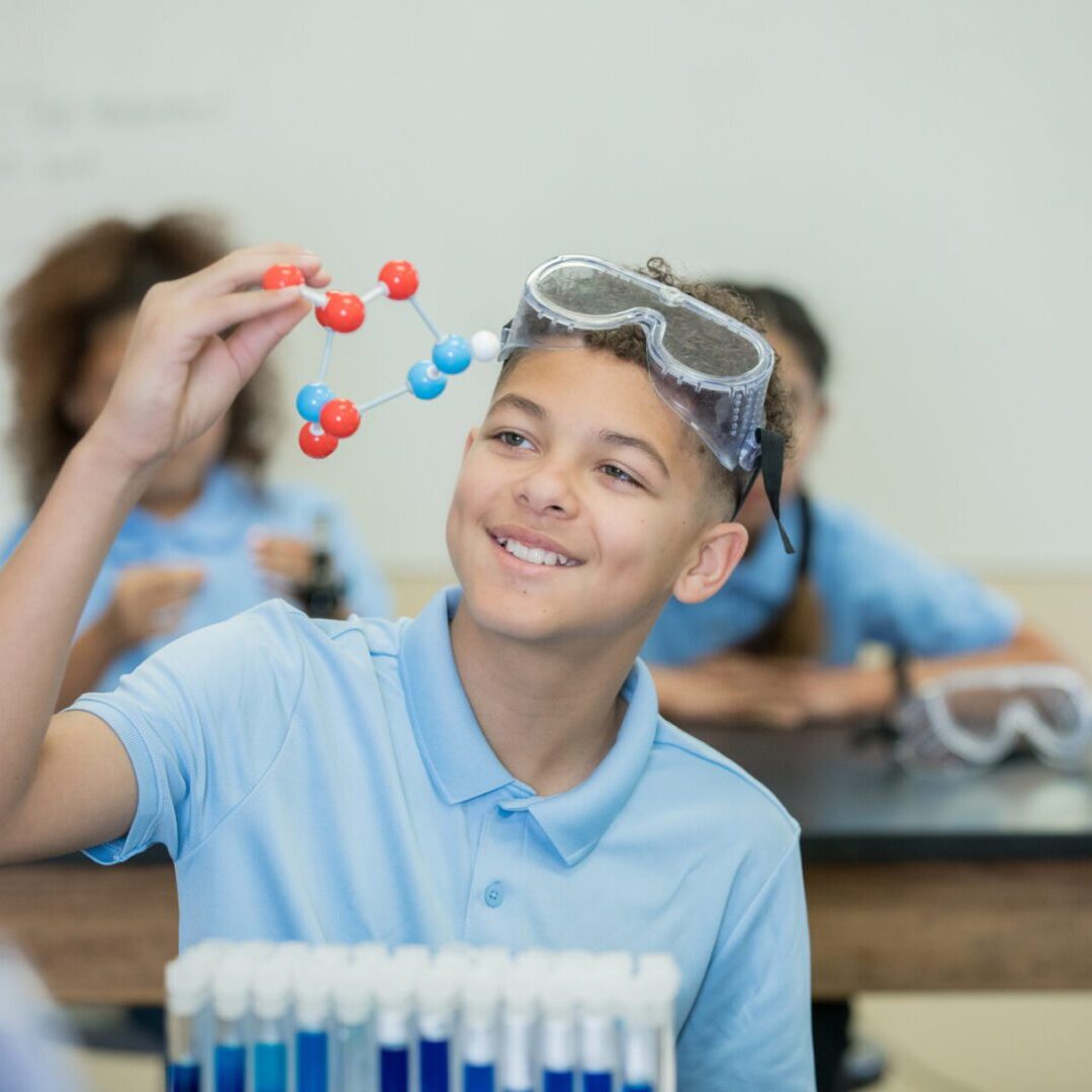 Student examining molecule model in classroom